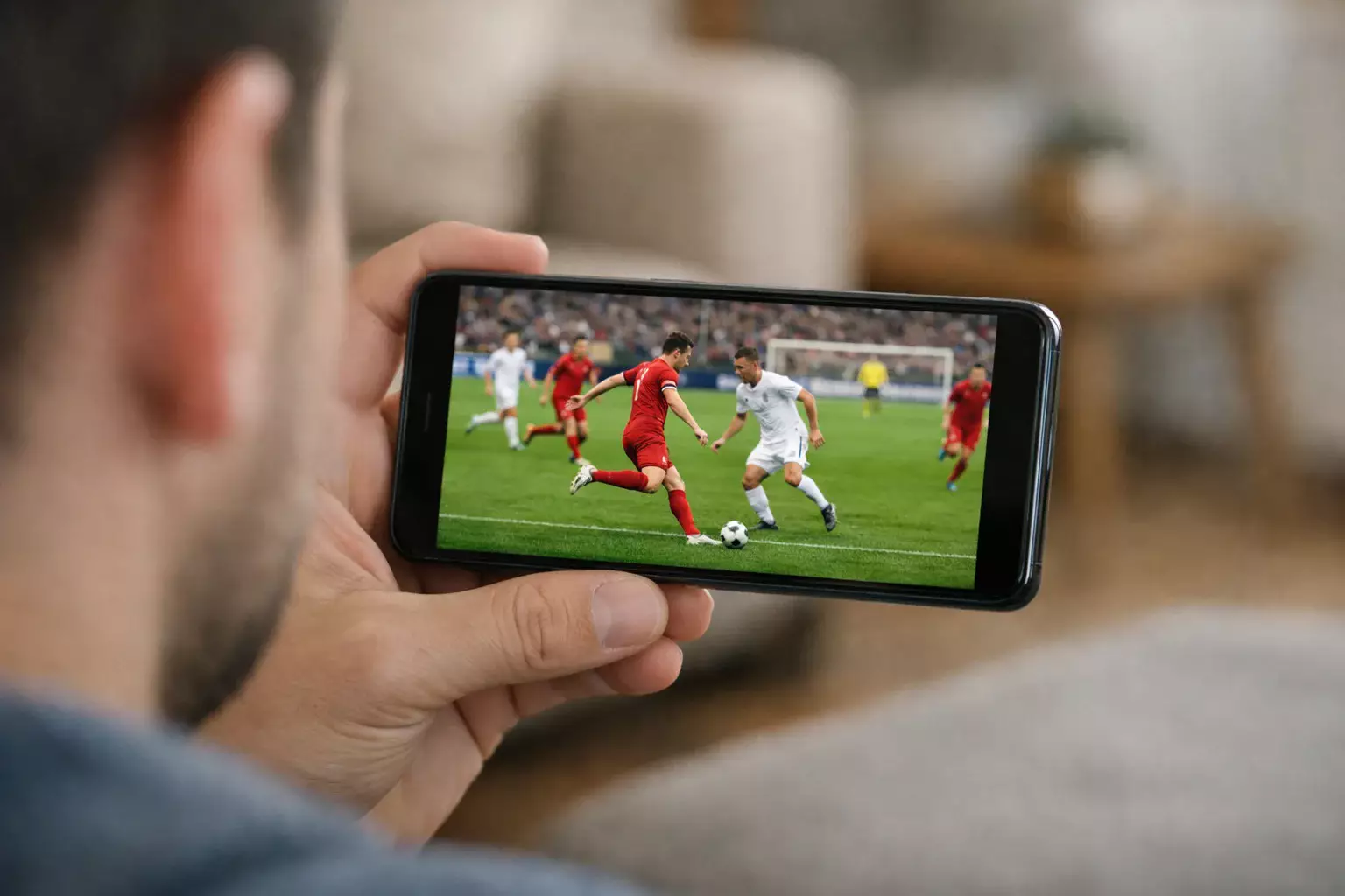 Smartphone con partita di calcio sullo schermo tenuto in mano